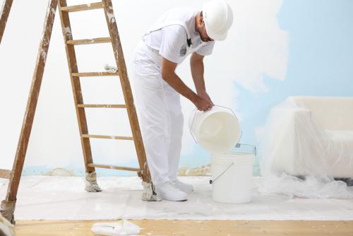 painter man at work pour into the bucket color for painting the wall
